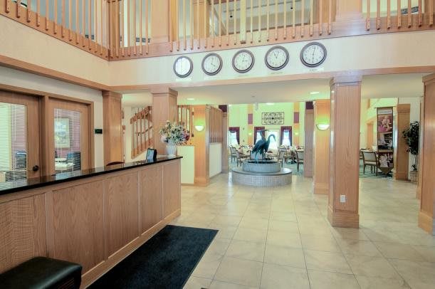 A modern hotel lobby featuring a reception desk, clocks displaying different time zones, and a stylish waiting area.