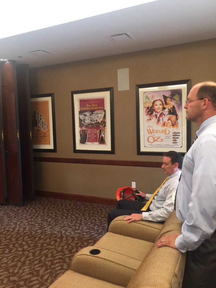 Two people in an office meeting room with movie posters on the wall.