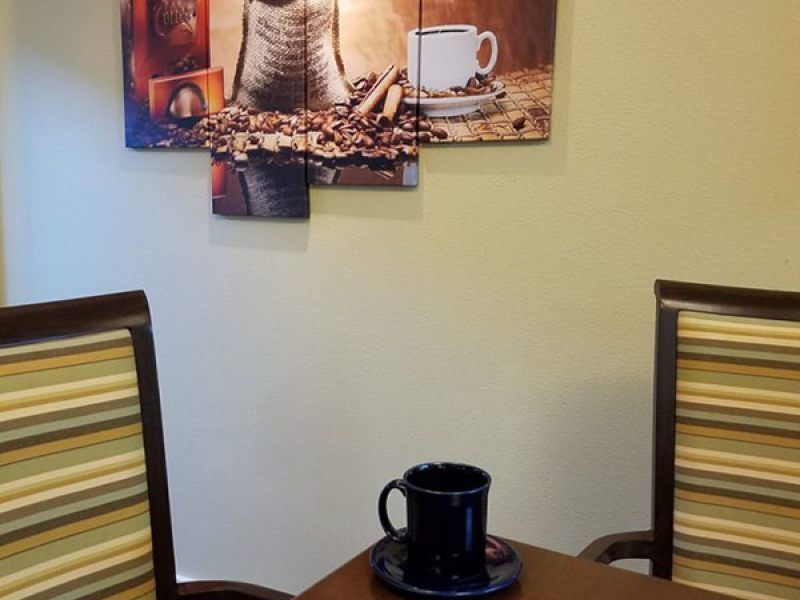 A cozy coffee-themed setting with a mug on the table and artwork on the wall.
