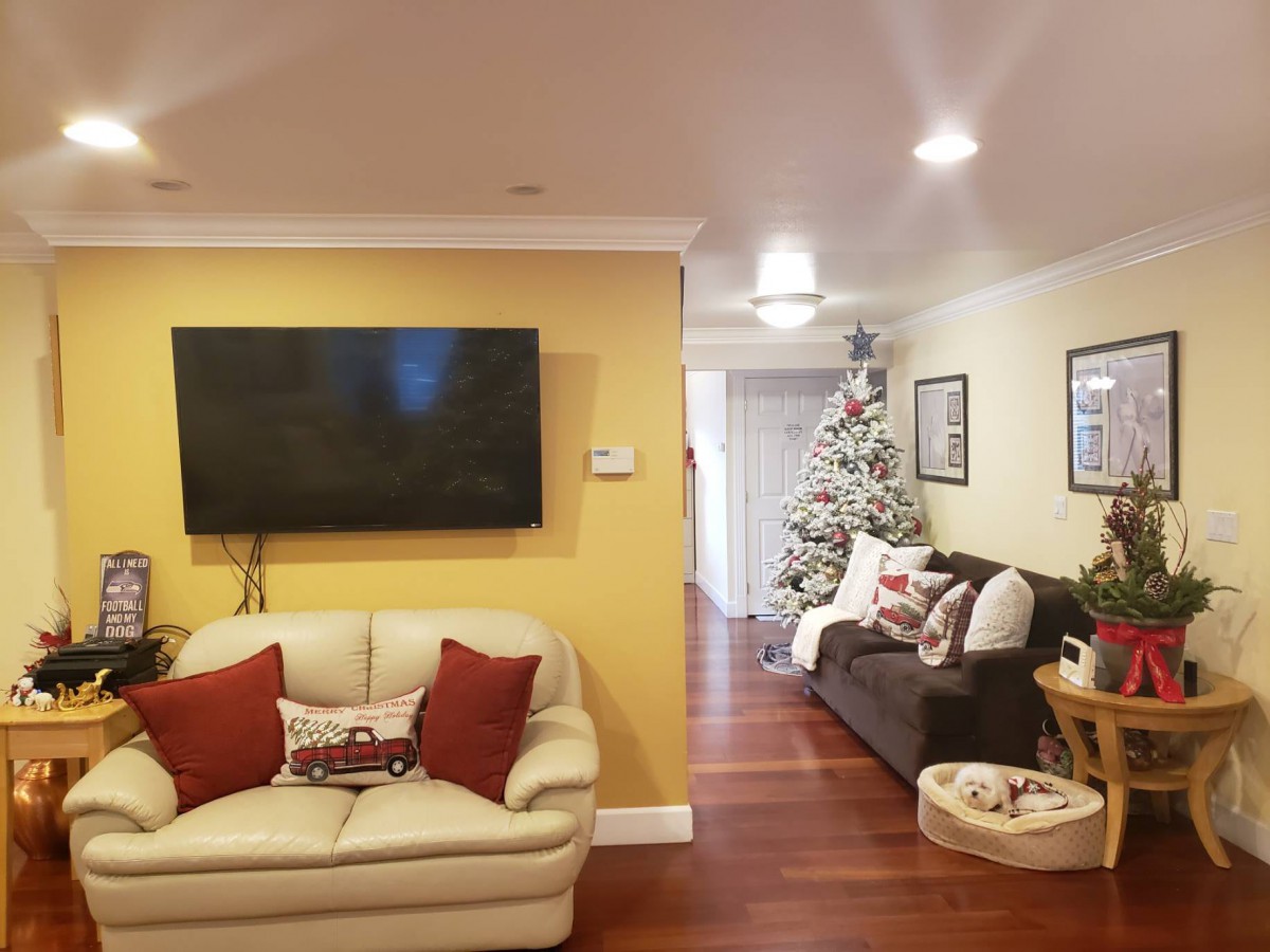 A cozy living room with festive Christmas decorations and a large TV on the wall.