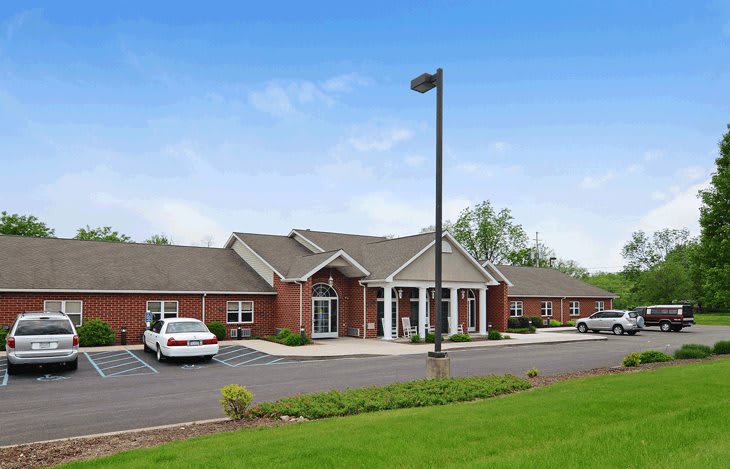 A brick building with a parking lot and lamp post on a clear day.