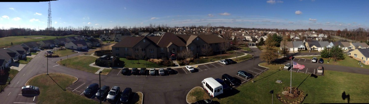 Aerial view of a suburban residential area with buildings and parked vehicles.