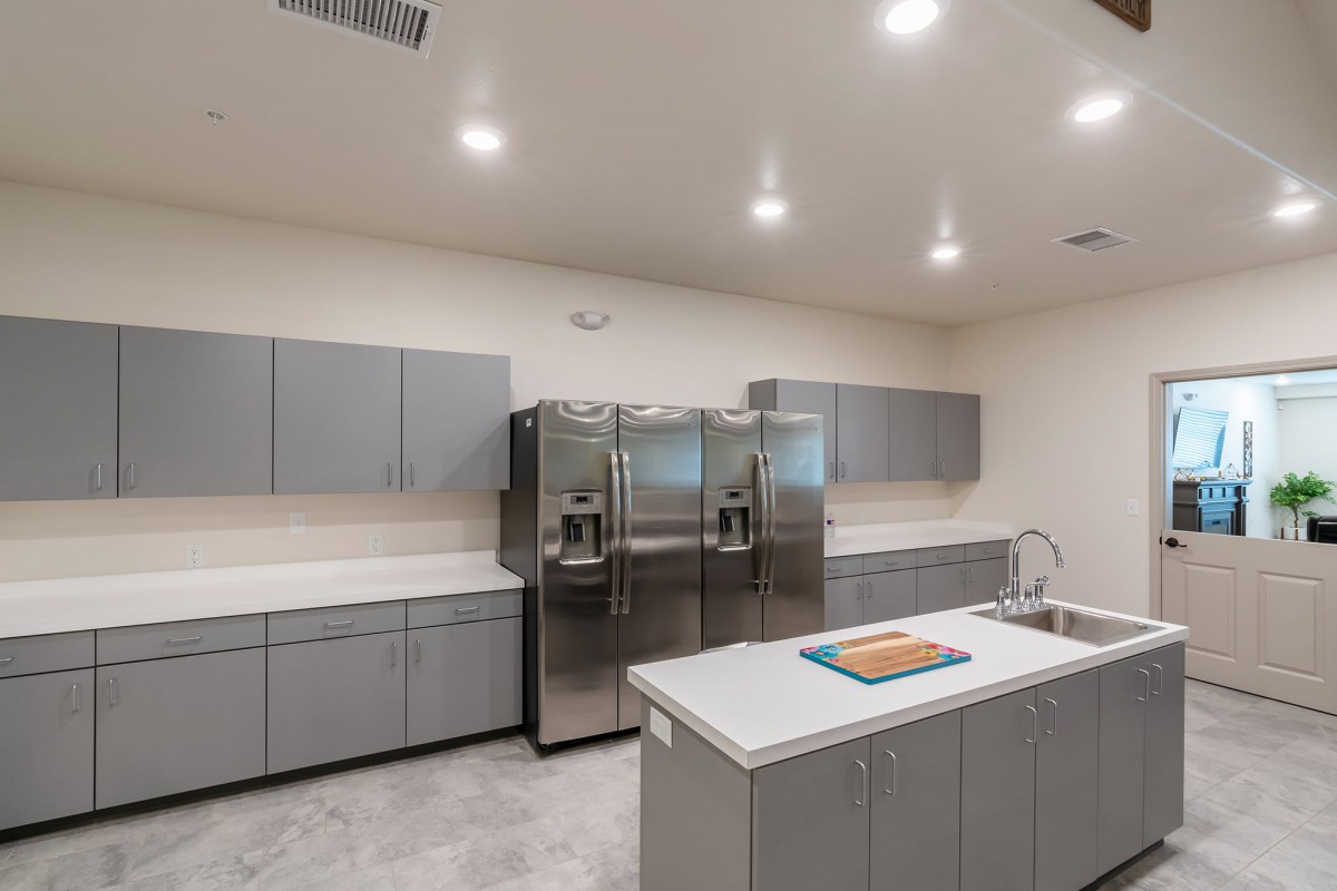 A modern kitchen interior with gray cabinets, stainless steel appliances, and a central island.