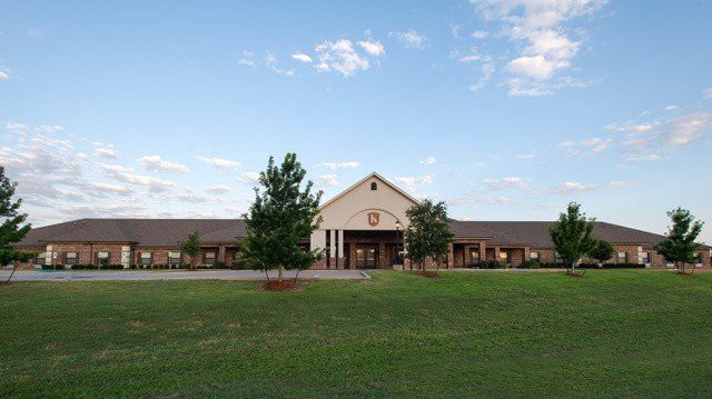 A picturesque view of a school building with a spacious lawn and clear sky.