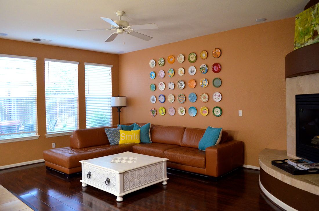 A cozy living room featuring a leather sectional sofa, colorful wall art, and a white coffee table.