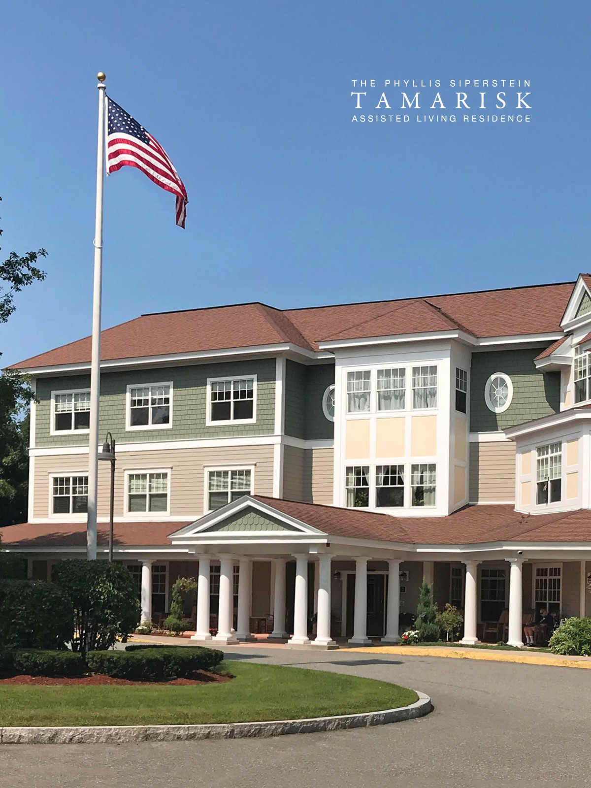 A three-story building with an American flag in front, featuring classic architectural design.