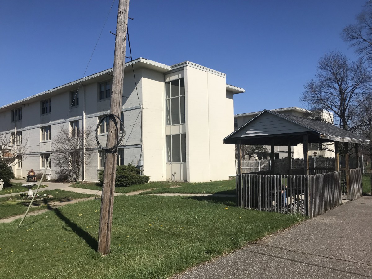 A suburban apartment building with a nearby gazebo and grassy area.