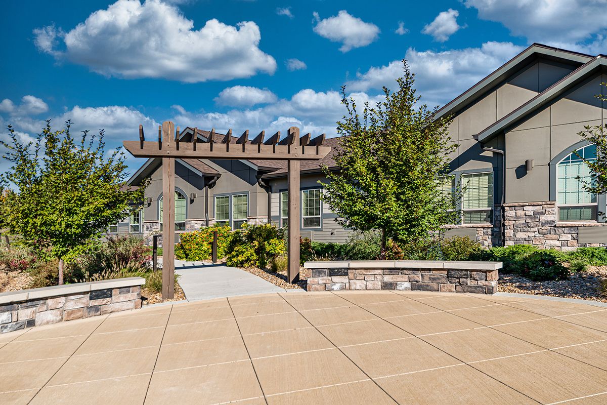 A house with a pergola and patio under a partly cloudy sky.
