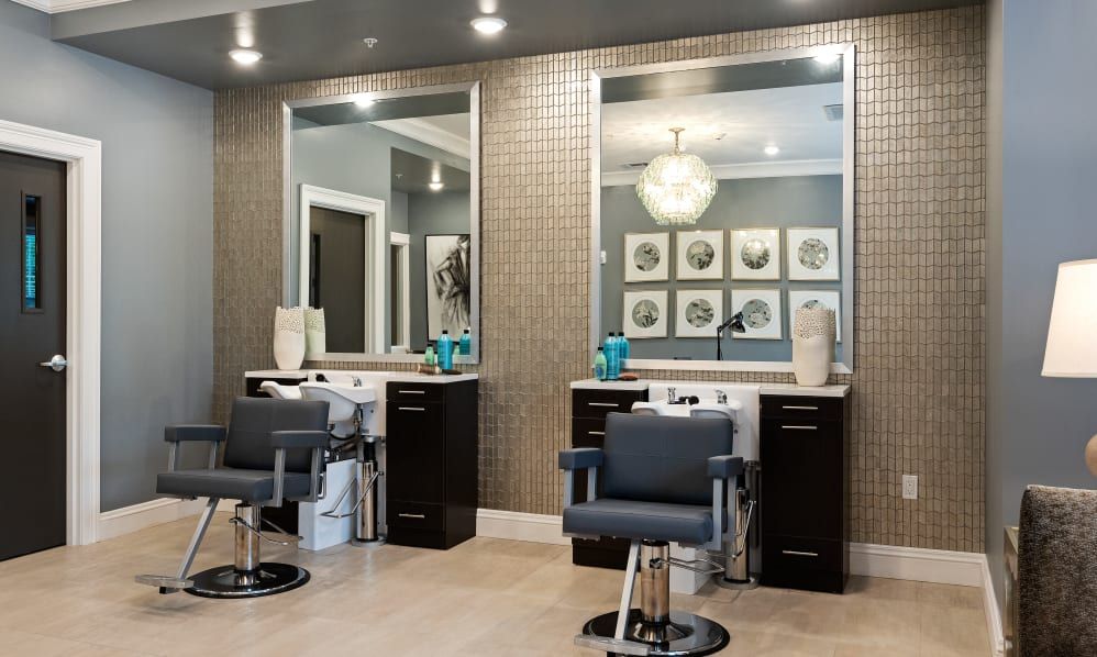 A modern beauty salon interior with stylish chairs and large mirrors.