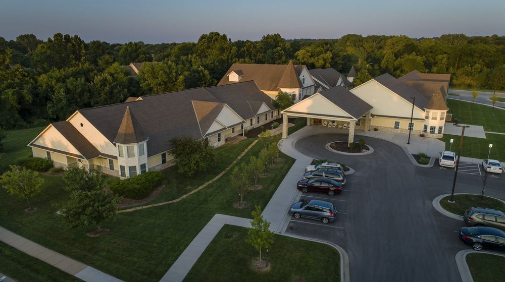 An aerial view of a cluster of buildings surrounded by lush greenery and a small parking lot.