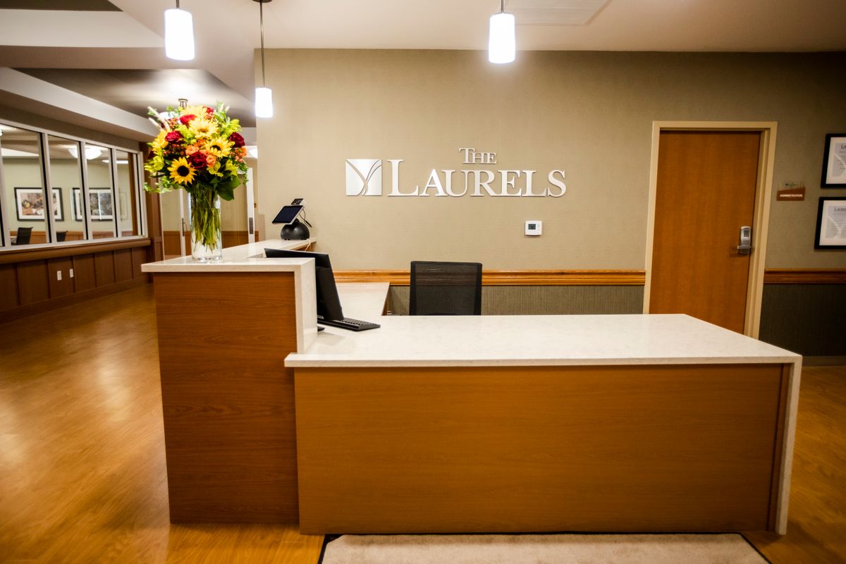 A modern office reception desk with flowers and signage.