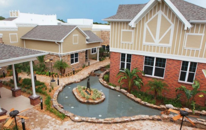 A scenic view of buildings surrounding a small landscaped pond and garden walkway.