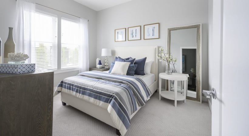 A modern minimalist bedroom with a neatly made bed, decorative pillows, and contemporary furnishings.