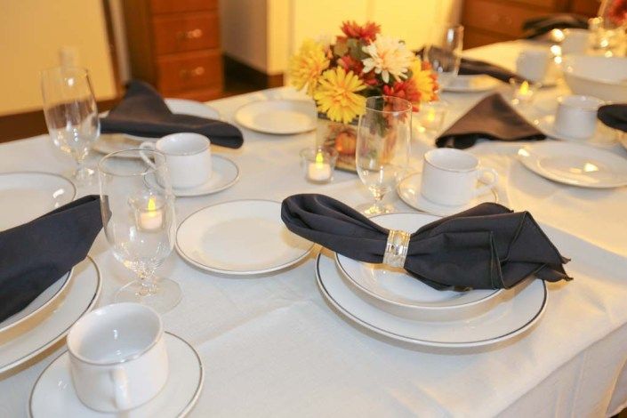 An elegantly set dining table with a floral centerpiece and candles.