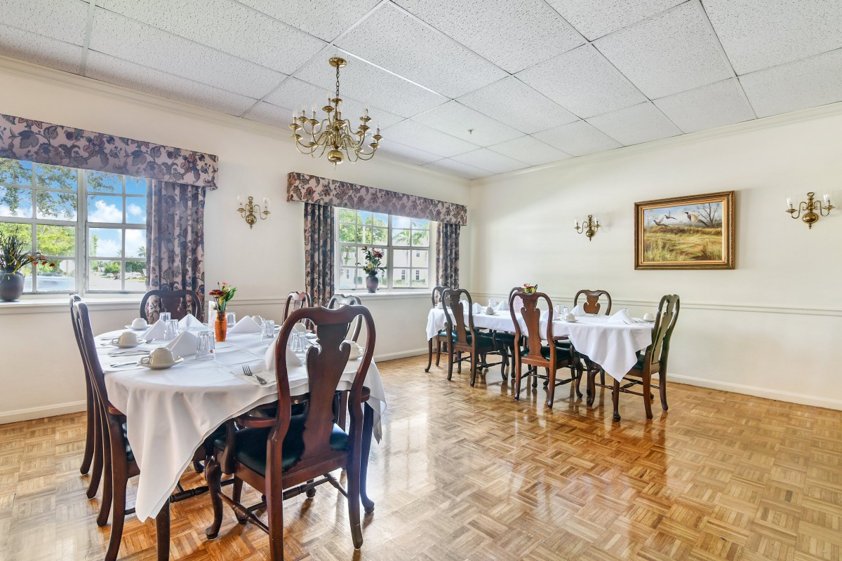 A traditional dining room with elegantly set tables and a chandelier.