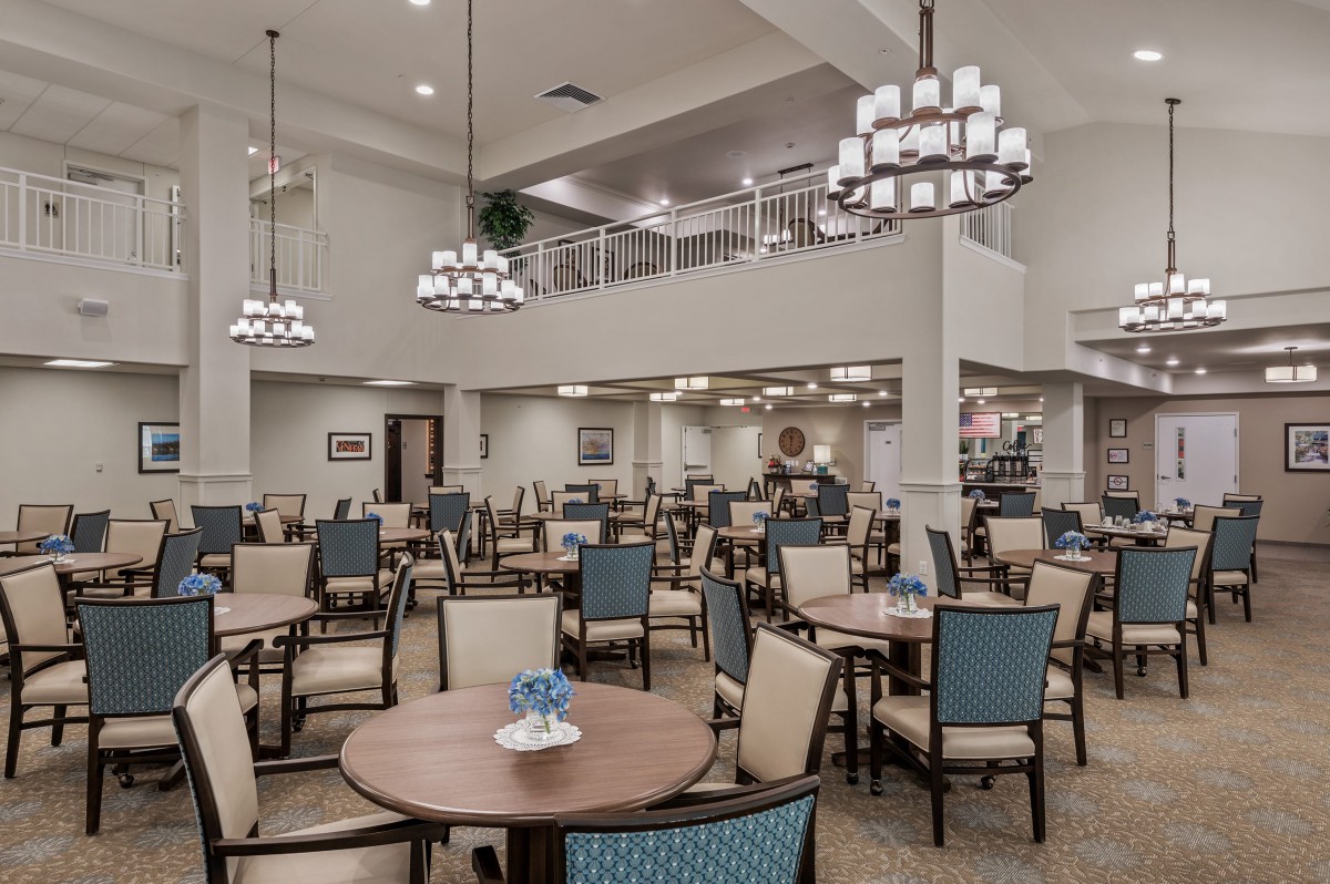Spacious dining area with elegant chandeliers and neatly arranged tables and chairs.