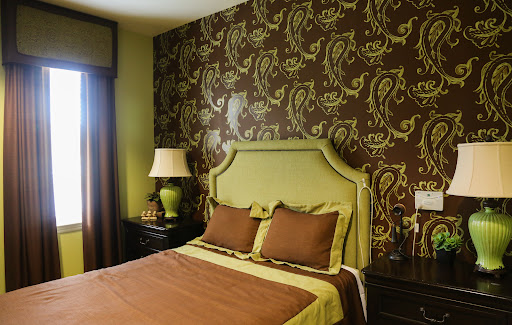 A stylishly decorated bedroom featuring a patterned wallpaper and coordinated bedding.