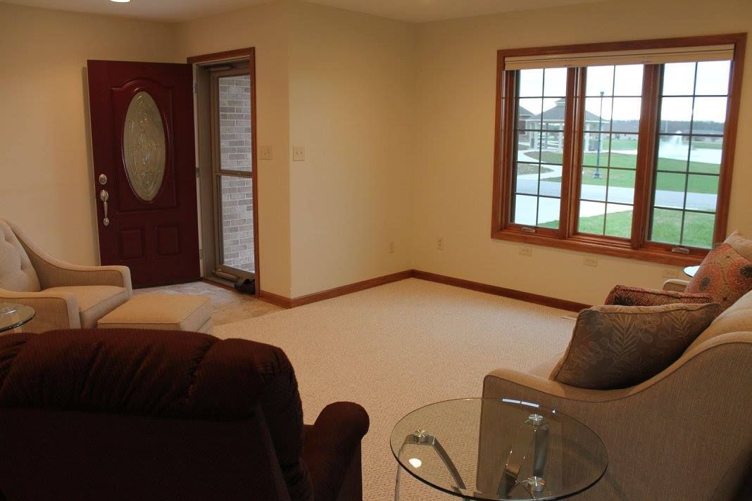 A cozy living room with a sofa, armchair, and large window offering a view outside.