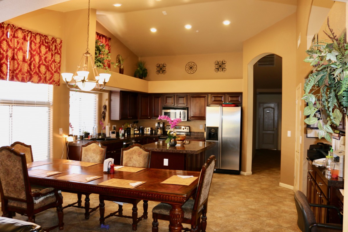 A modern open kitchen with a dining area featuring wooden furniture and stainless steel appliances.