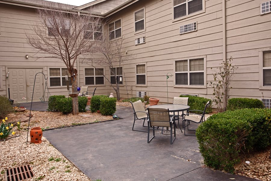A quiet residential patio area with outdoor seating and surrounding greenery.
