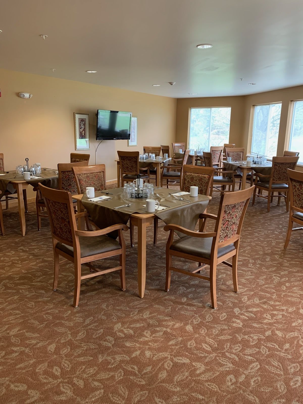 An empty dining room with neatly arranged tables and chairs, ready for guests.