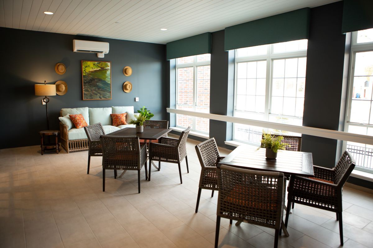 A modern dining and living area with natural light streaming through large windows, featuring stylish furniture and decor.