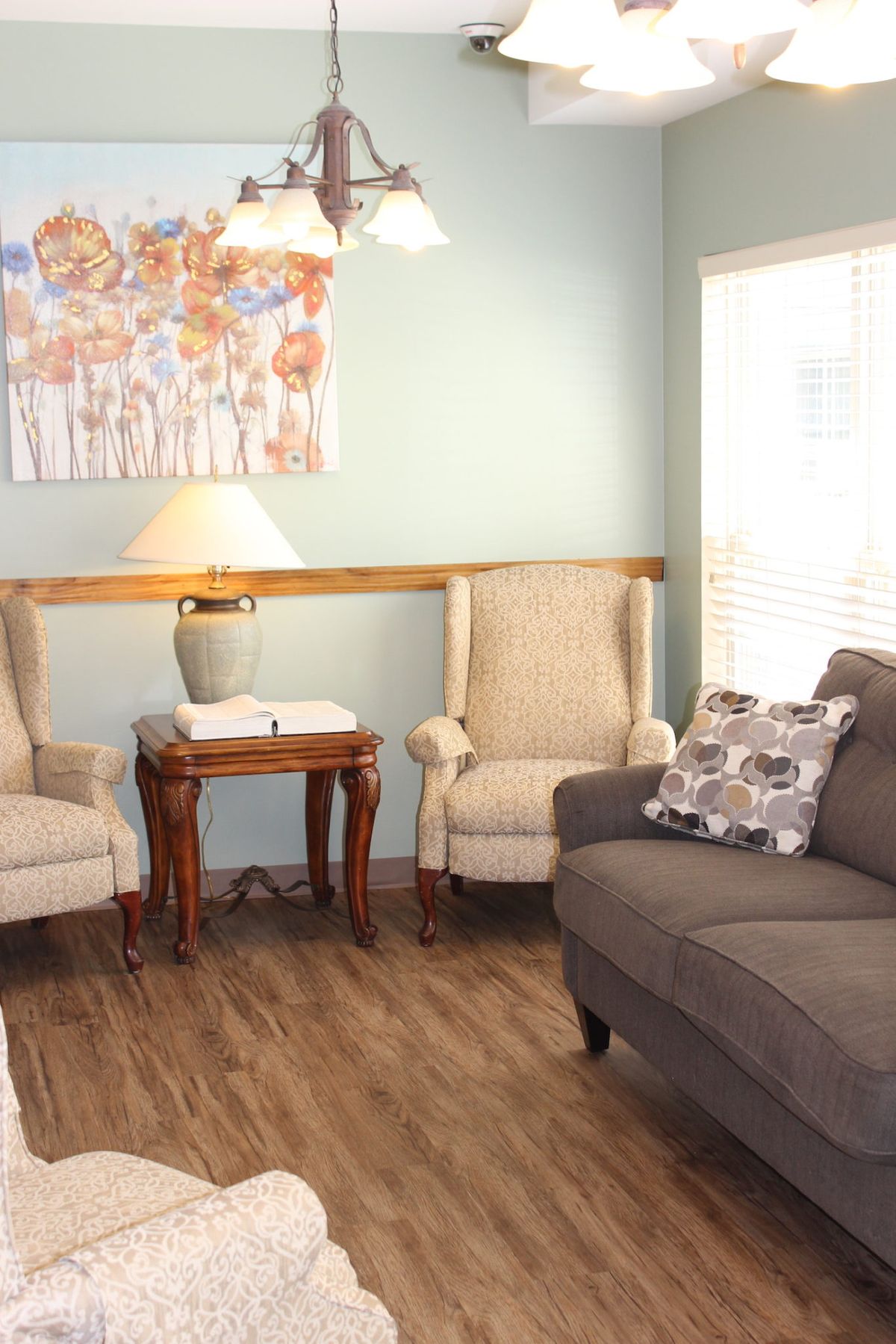 A cozy living room with armchairs, a sofa, and a side table under soft lighting.