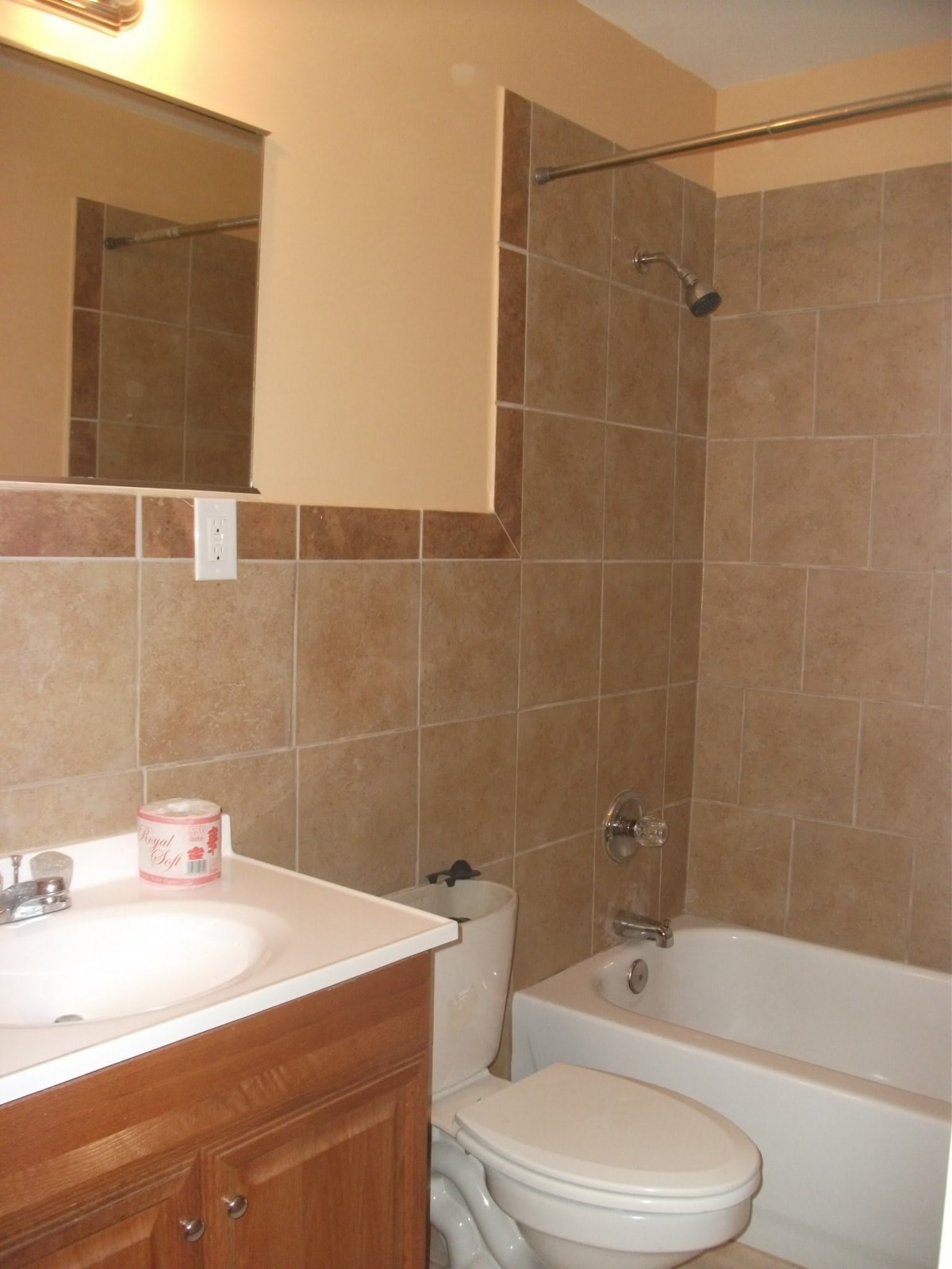A bathroom with tiled walls featuring a sink, toilet, and bathtub.