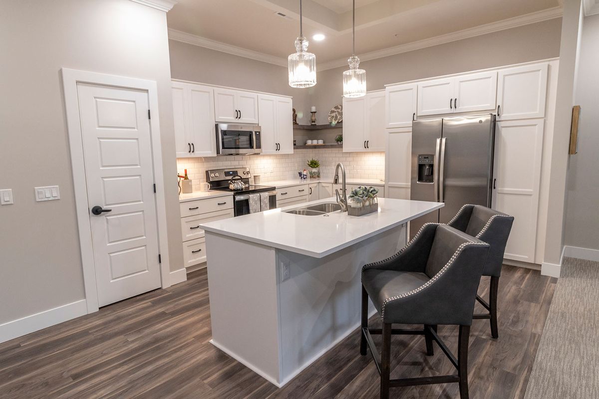 A modern kitchen with white cabinets, an island, and stainless steel appliances.