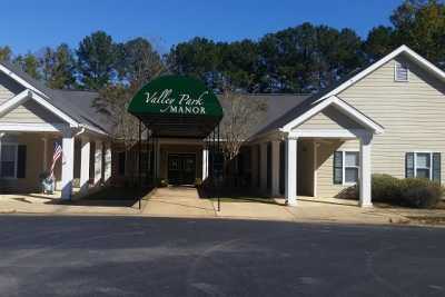 The entrance of a building with an awning labeled 'Valley Park Manor', surrounded by trees.