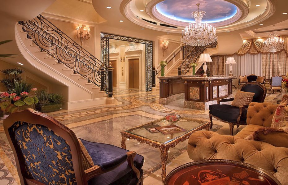 A luxurious hotel lobby with elegant decor, featuring a grand chandelier and marble flooring.