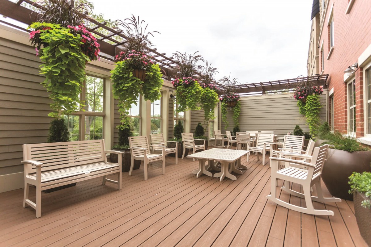 A cozy outdoor patio with wooden furniture and lush hanging plants.