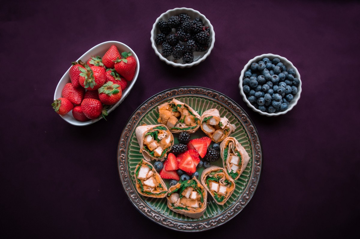 A platter of assorted canaps surrounded by bowls of strawberries, blackberries, and blueberries.