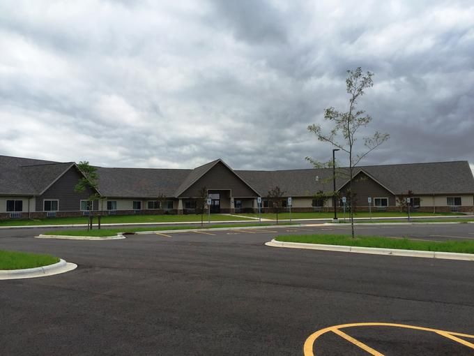 A large building with an empty parking lot under a cloudy sky.