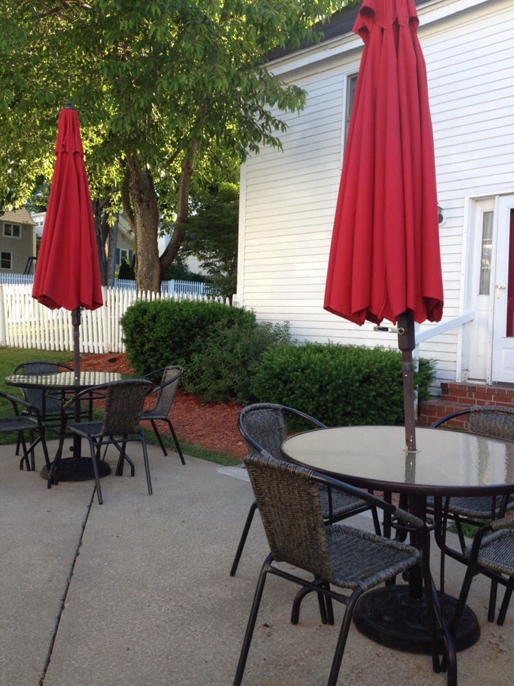A peaceful outdoor patio with tables, chairs, and red umbrellas.