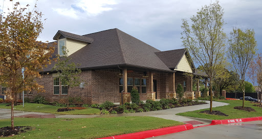 A modern residential building with a brick facade and a well-maintained lawn.