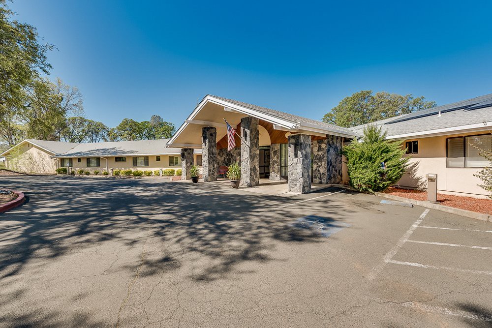 A motel entrance with a parking lot on a clear, sunny day.