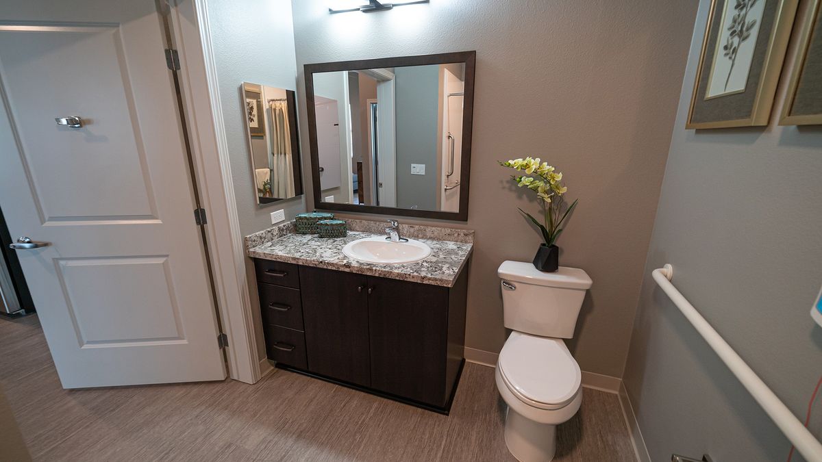 A modern bathroom featuring a vanity with a granite countertop, large mirror, and elegant decor.