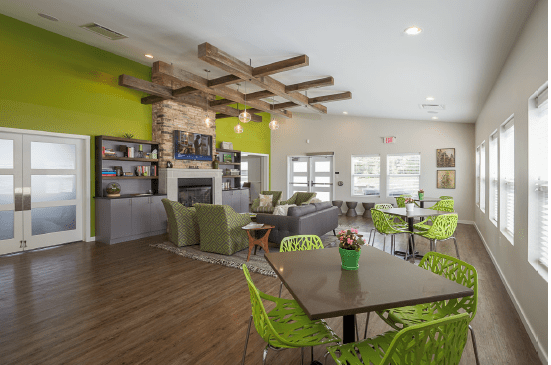 Modern interior with vibrant green accents and a cozy seating area featuring a fireplace and wooden beam ceiling.
