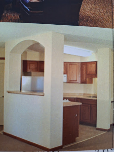 A cozy kitchen featuring wooden cabinets and an open archway that connects to the dining area.