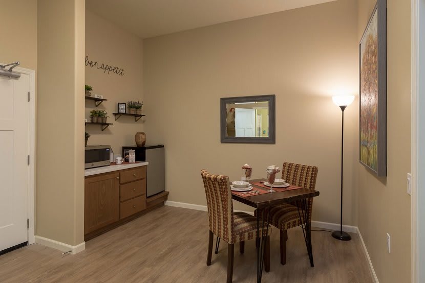 A cozy dining area with a small table set for two, adjacent to a kitchenette.