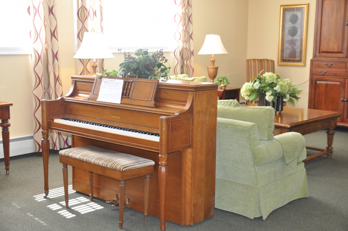 A cozy living room with a wooden piano and comfortable seating.