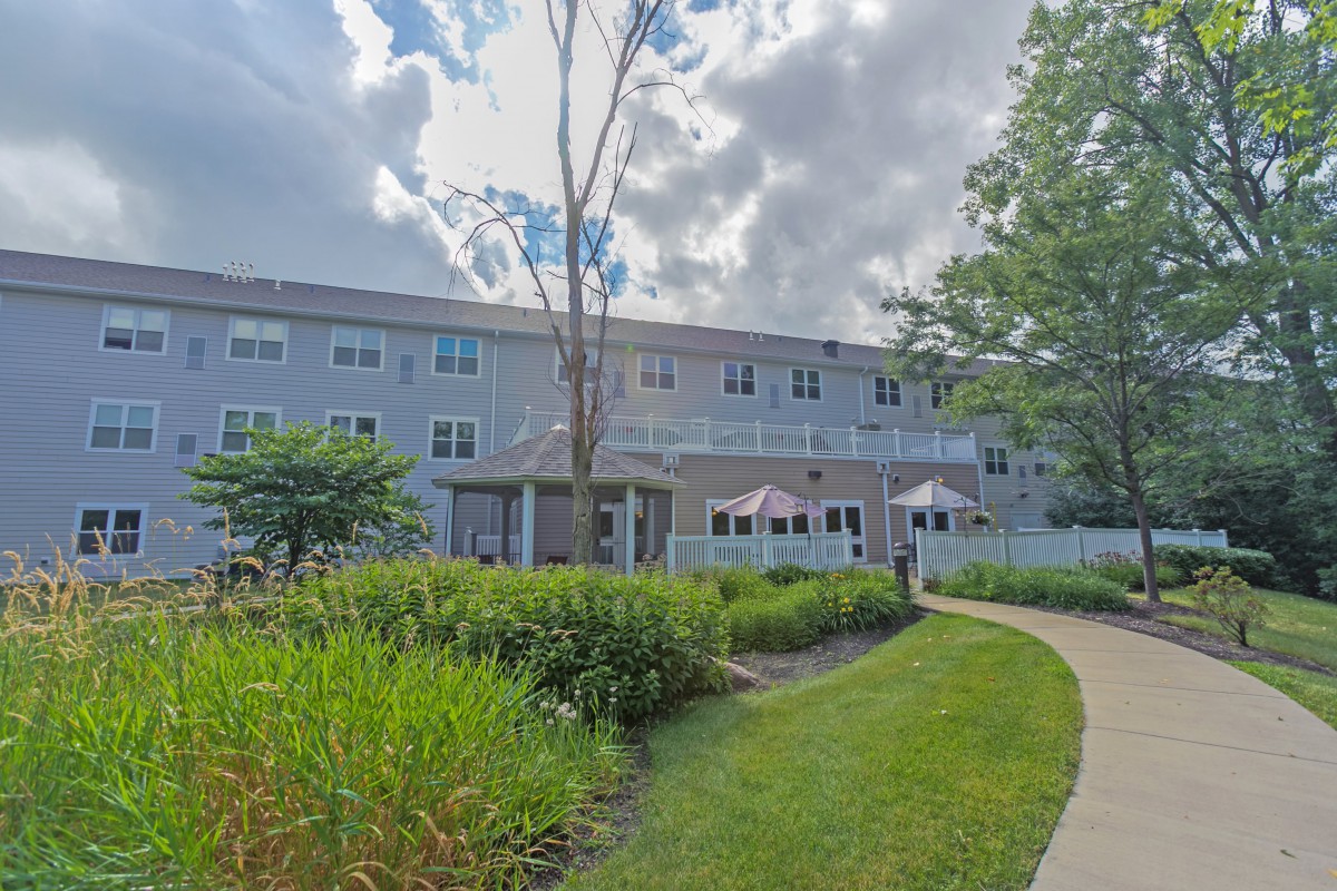 A residential building with a well-maintained garden and pathway under a cloudy sky.
