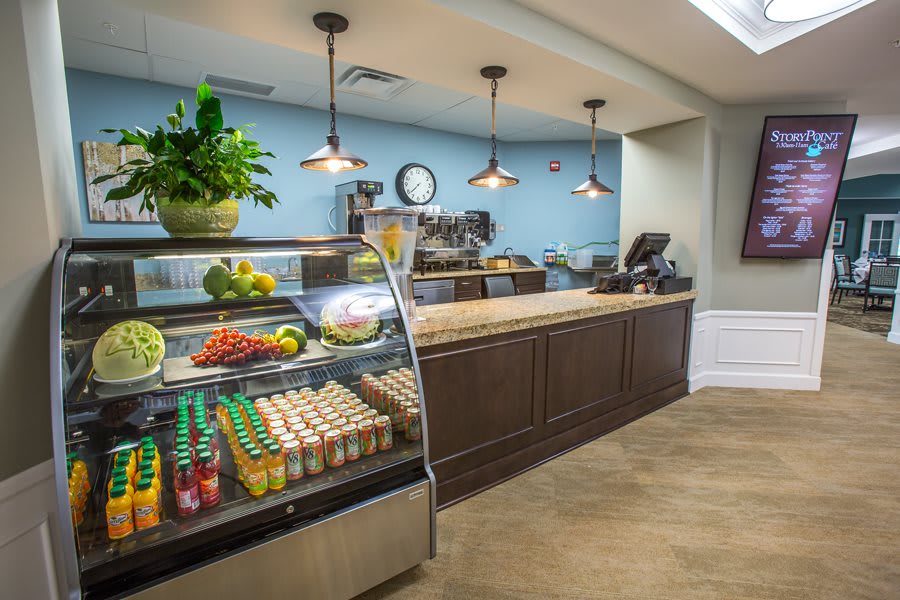 A modern cafe interior with a display case containing drinks and fresh produce.