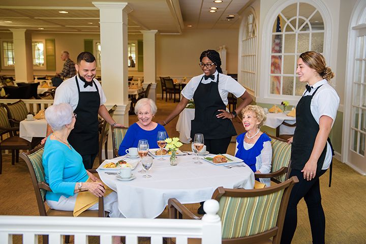 A group of elderly individuals enjoying a meal together at a restaurant, attended by waitstaff.
