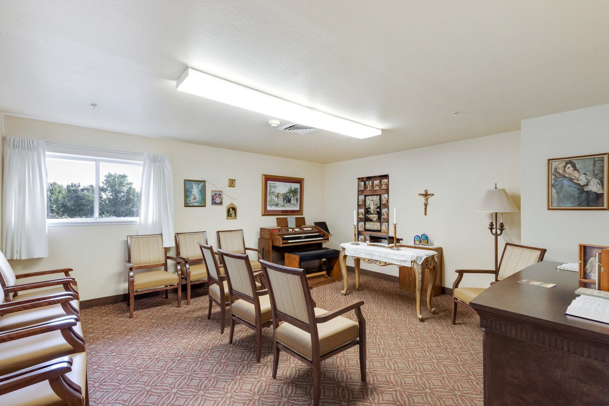 A small chapel with several chairs, an organ, and religious decorations.
