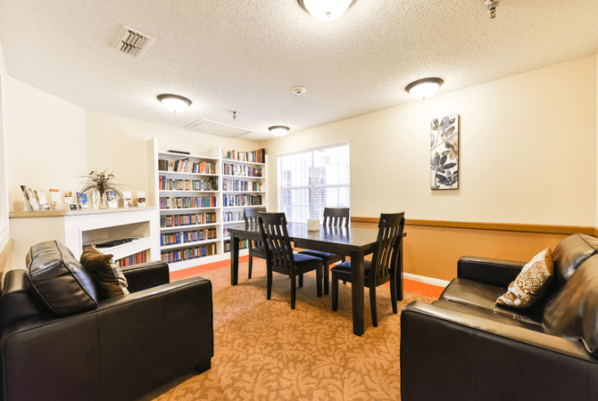 A cozy library interior with bookshelves, a table, and chairs for reading.