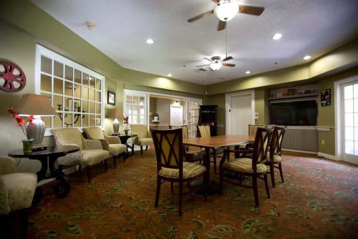 A cozy living room with a seating area, table, and ceiling fans.