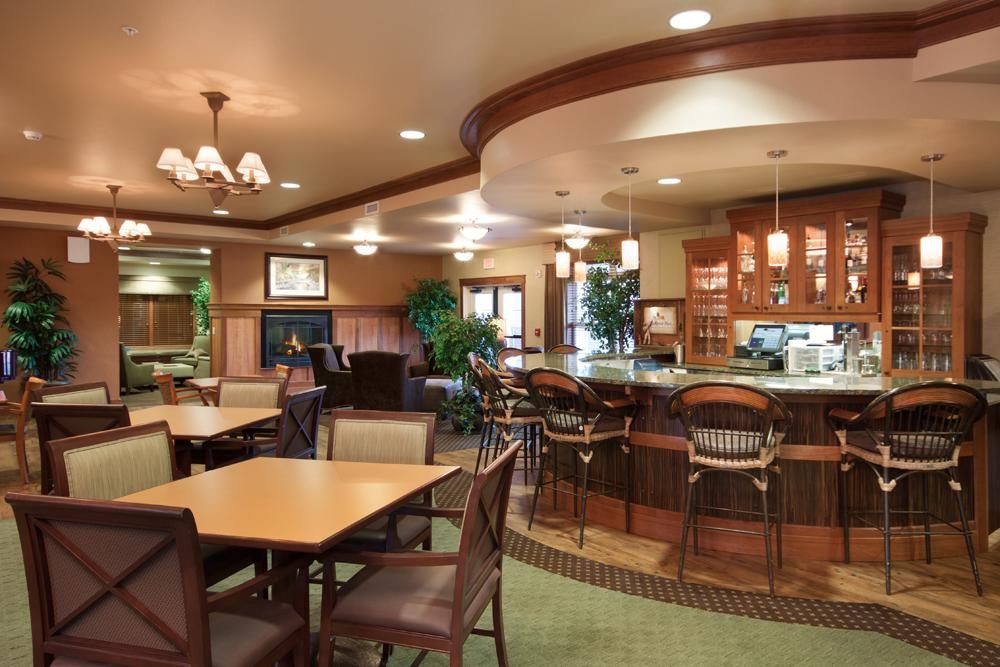 A cozy restaurant interior featuring a bar and dining area with wooden furniture.