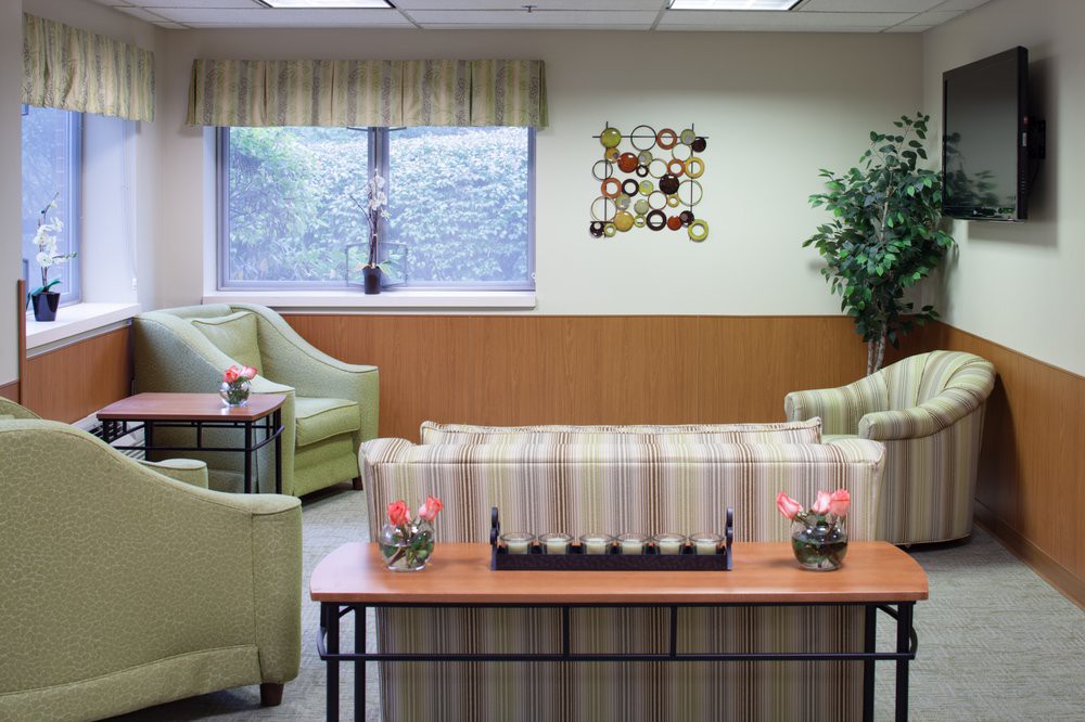 A cozy waiting room with comfortable seating, a central table, and decorative wall art.